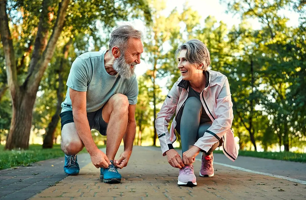 an elderly couple tying their shoes before exercise