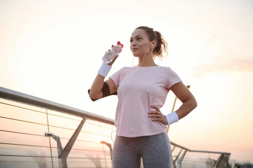 woman drinking water after running