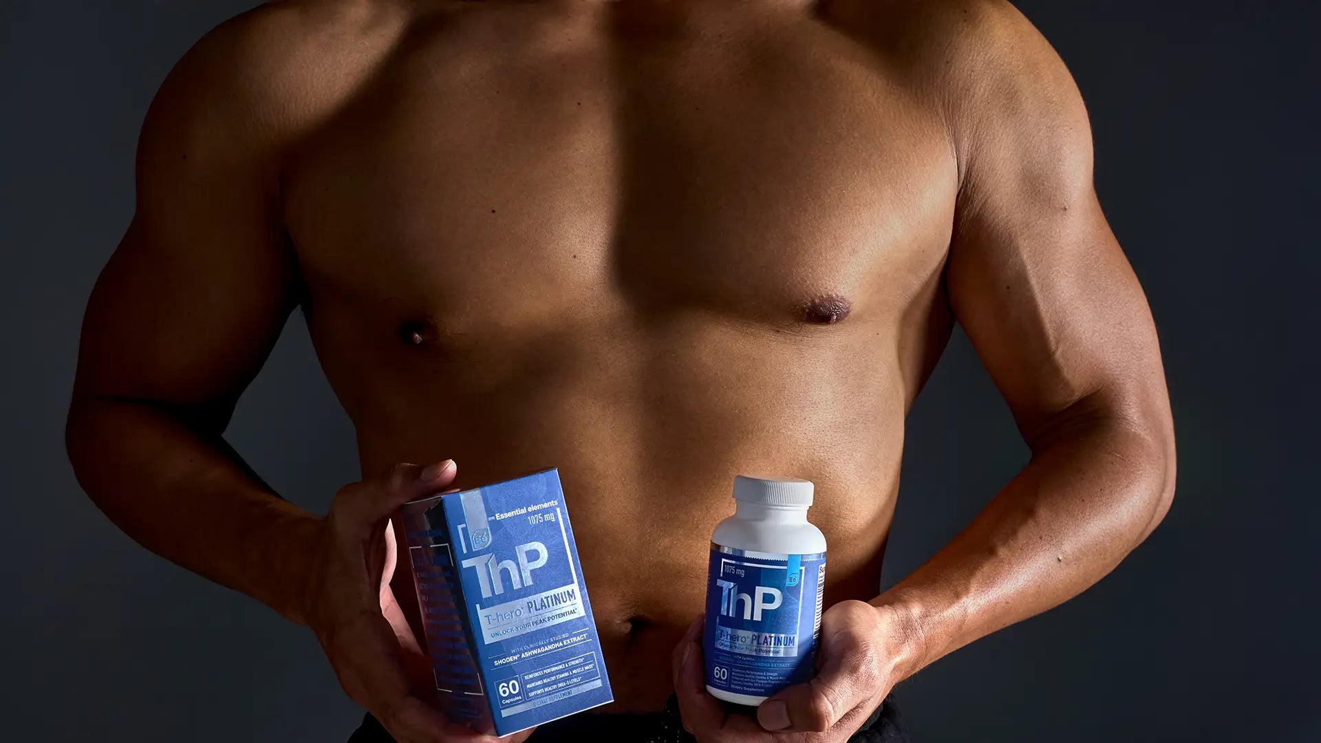 muscular man holding Essential elements' Testosteron hero Platinum products in his hands