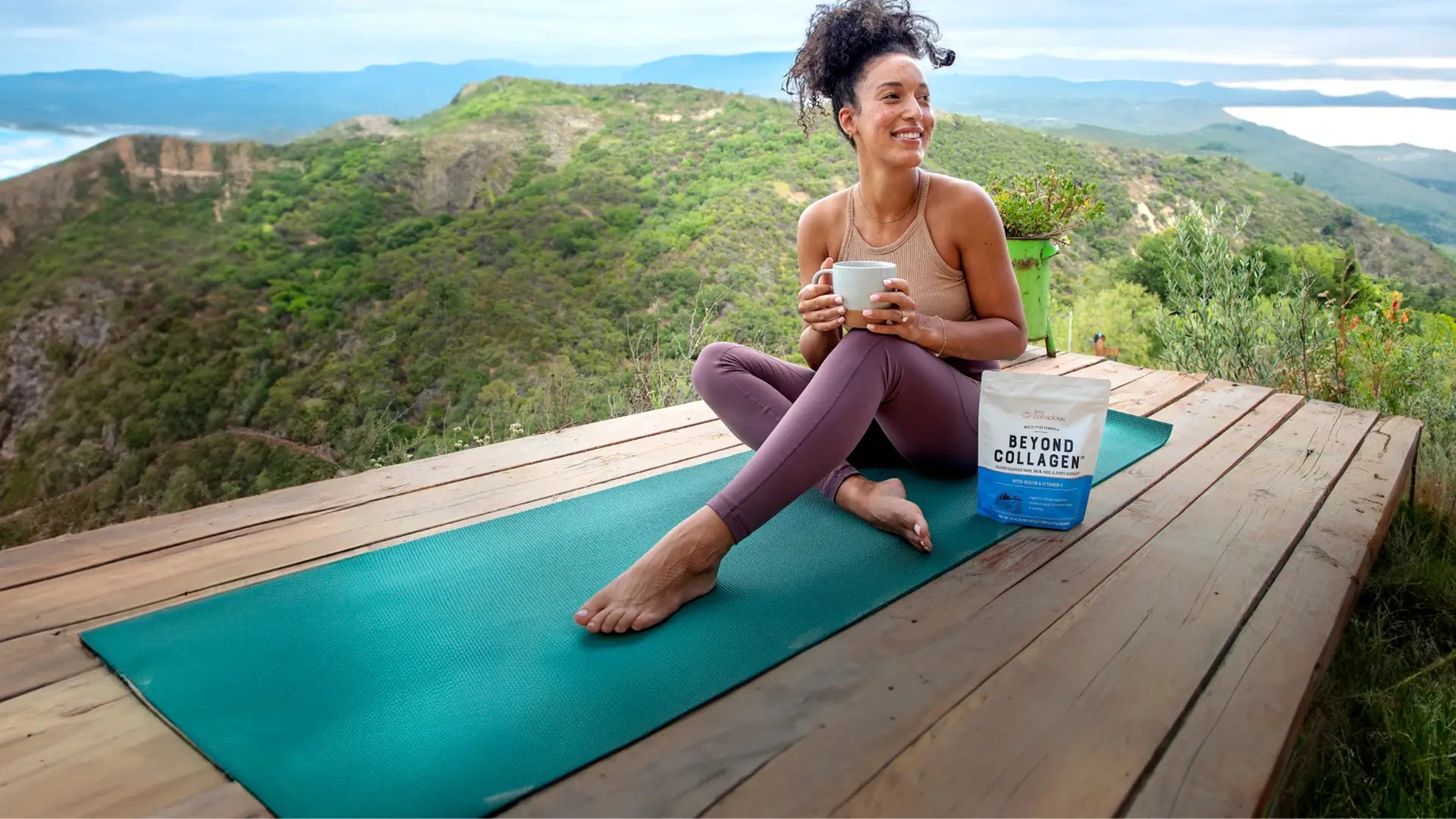 woman on a wooden desk at the edge of a hill on a yoga matt enjoying a beverage with Live Conscious Beyond Collagen in it